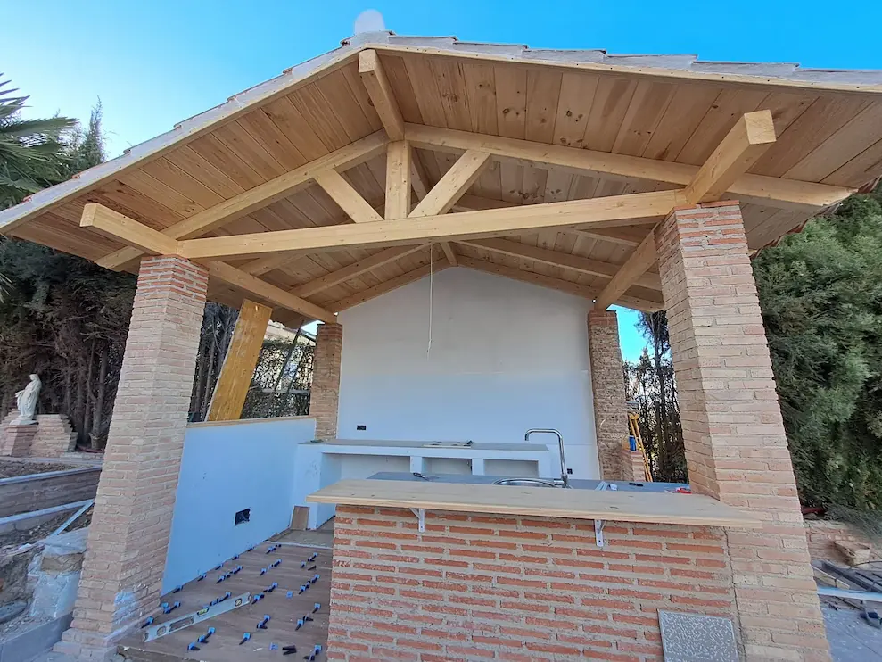 Reformas integrales en Granada: porche de obra nueva con estructura de madera y cocina exterior