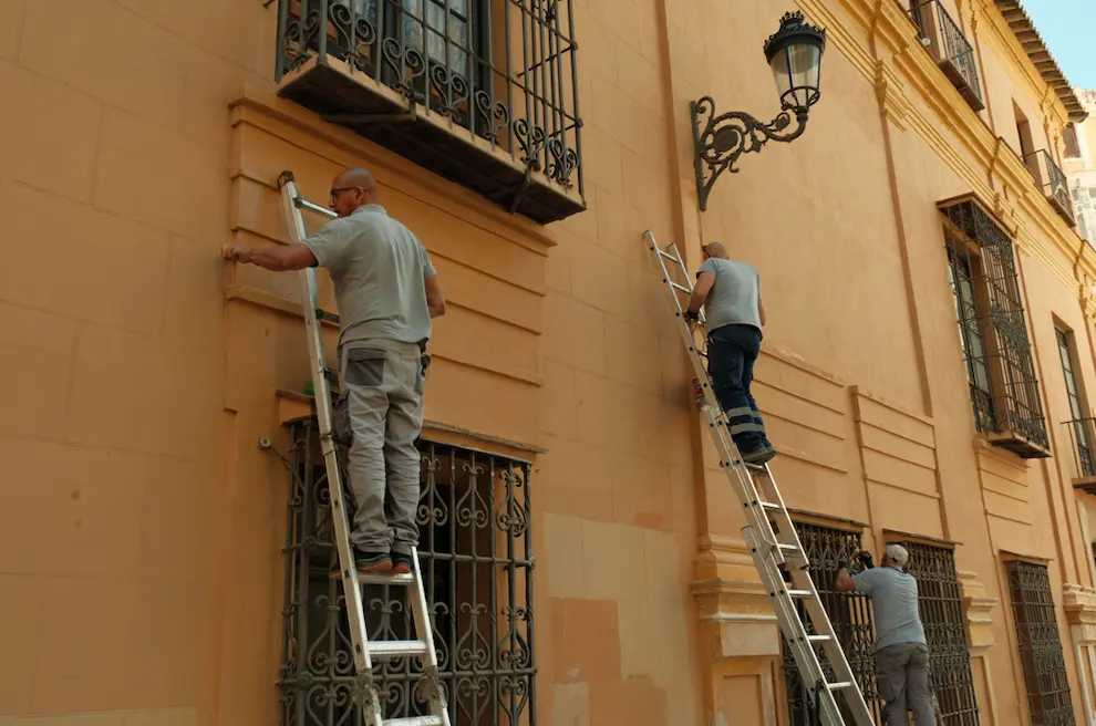 Rehabilitación de fachadas en Granada: operarios reparando la fachada de un edificio histórico