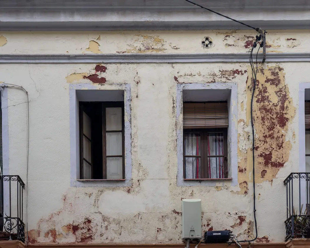 Rehabilitación de fachadas en Granada: fachada deteriorada con humedades y pintura desconchada