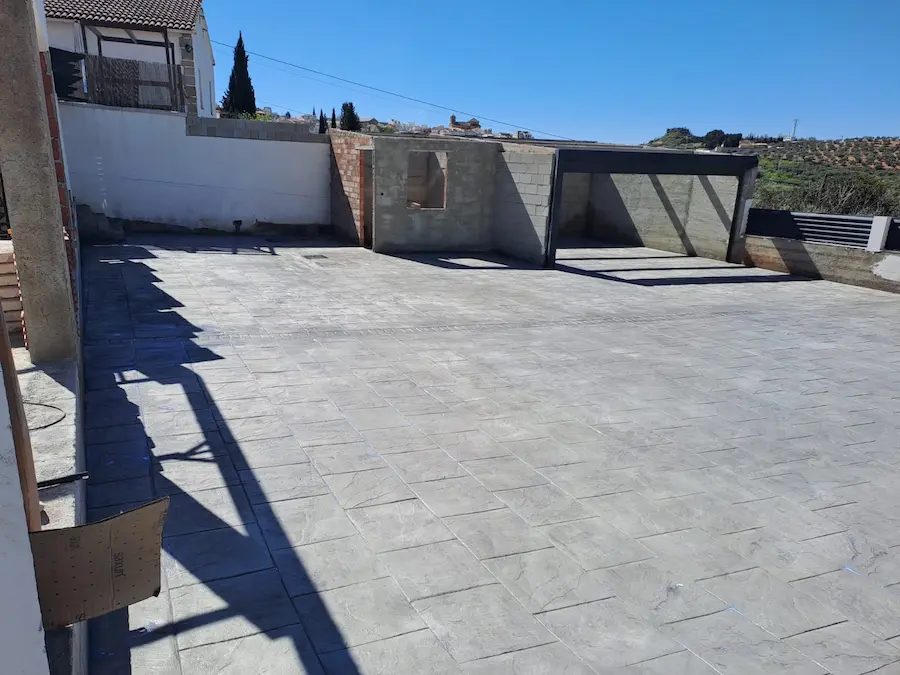 Constructora en Granada: patio de hormigón impreso y porche en una vivienda